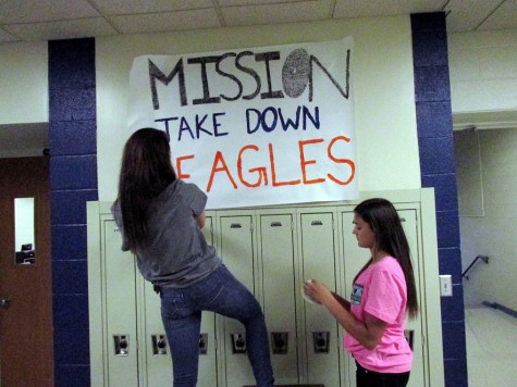 Makayla Carles and Abbey Luennsman hang signs in the high school to pep up the Blue Devils for the big game.
