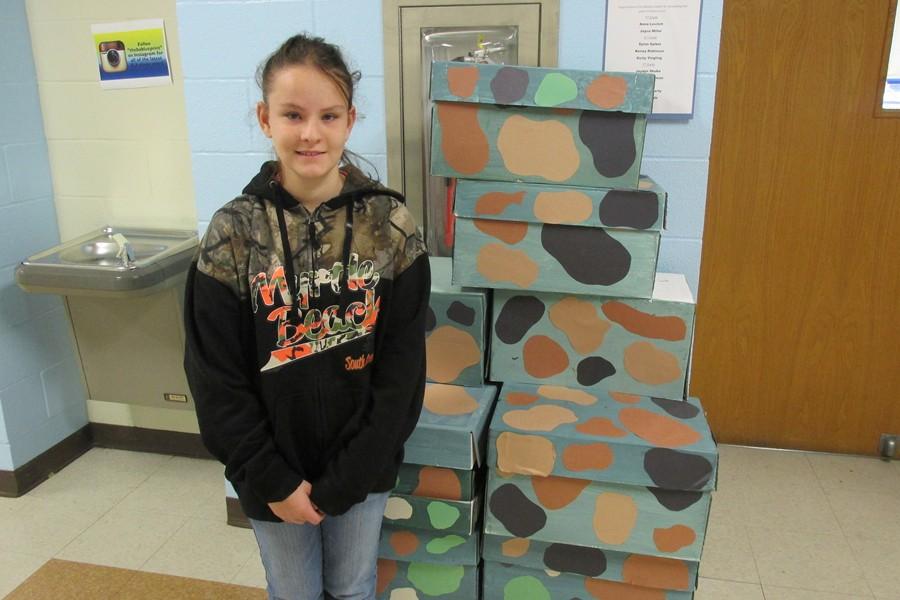 Middle schooler Paige Otto poses with supplies gathered for the SOS for Troops project.