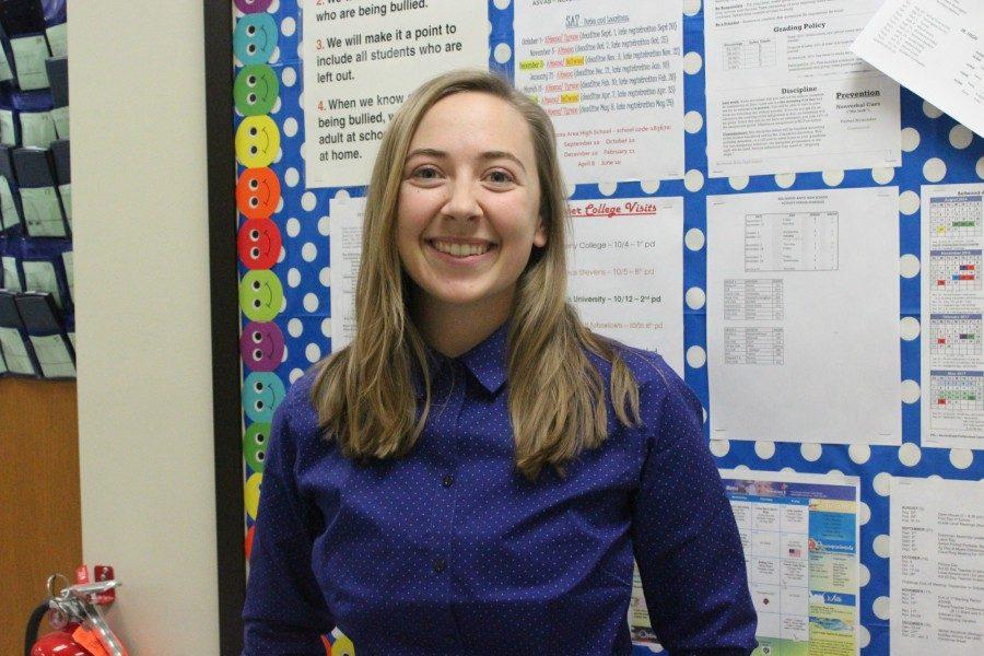 Ms. Clippard stands in front of her bulletin board where her students can find information about their classes.