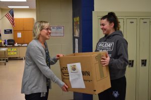 FCA member Emilie Leidig drops off a cereal drive collection box to Mrs. Bartlett's home room.