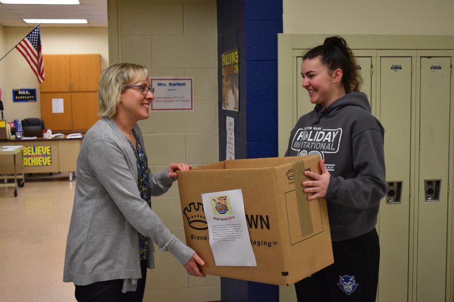 FCA member Emilie Leidig drops off a cereal drive collection box to Mrs. Bartletts home room.