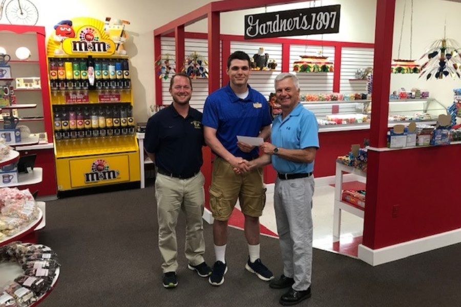 Caden Nagle receives a scholarship check from Gardners Candies president Sam Phillips with Coach Nick Lovrich.