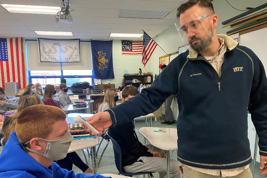 Civics teacher Mr. Matthew McNaul takes the temperature of Chance Schreier as part of B-As COVID 19 safety guidelines.