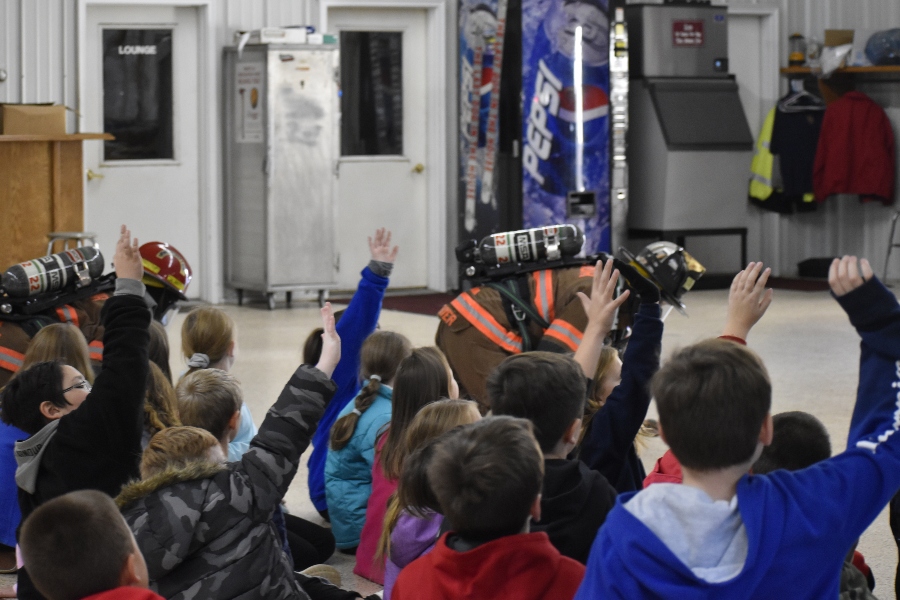 Myers students raise their hands to answer questions during a fire safety presentation at Excelsior Fire Hall.