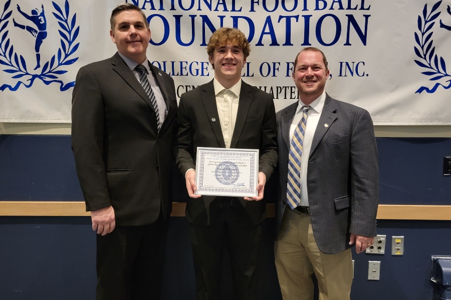 Gaven Ridgway (center) poses with high school principal Mr. Richard Schreier and football coach Mr. Nick Lovrich after receiving a scholarship from the National Football Foundation.