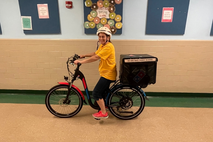 Mrs. Jodi rolls through the hallway delivering pizza to students at Myers.