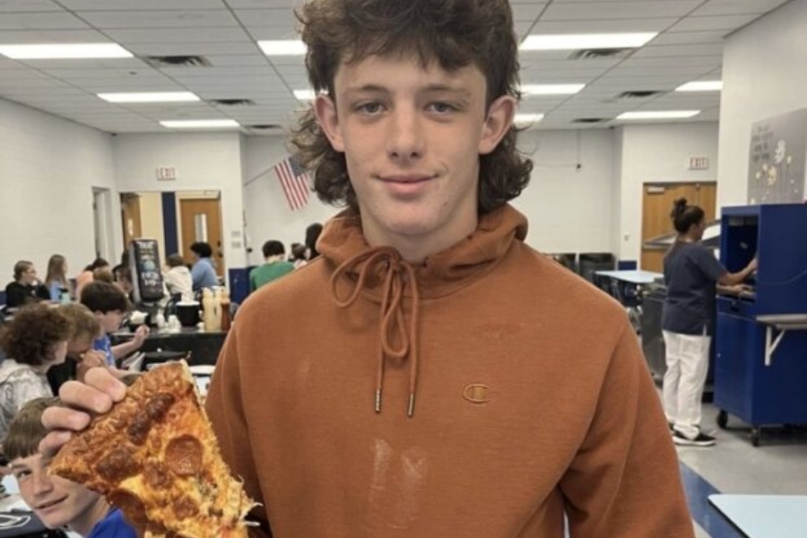 Connor Mayes dines on pepperoni pizza in the high school cafeteria.