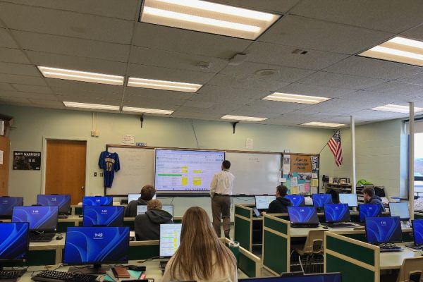 Mr. Hallahan checks out a spreadsheet with students in his financial literacy class.