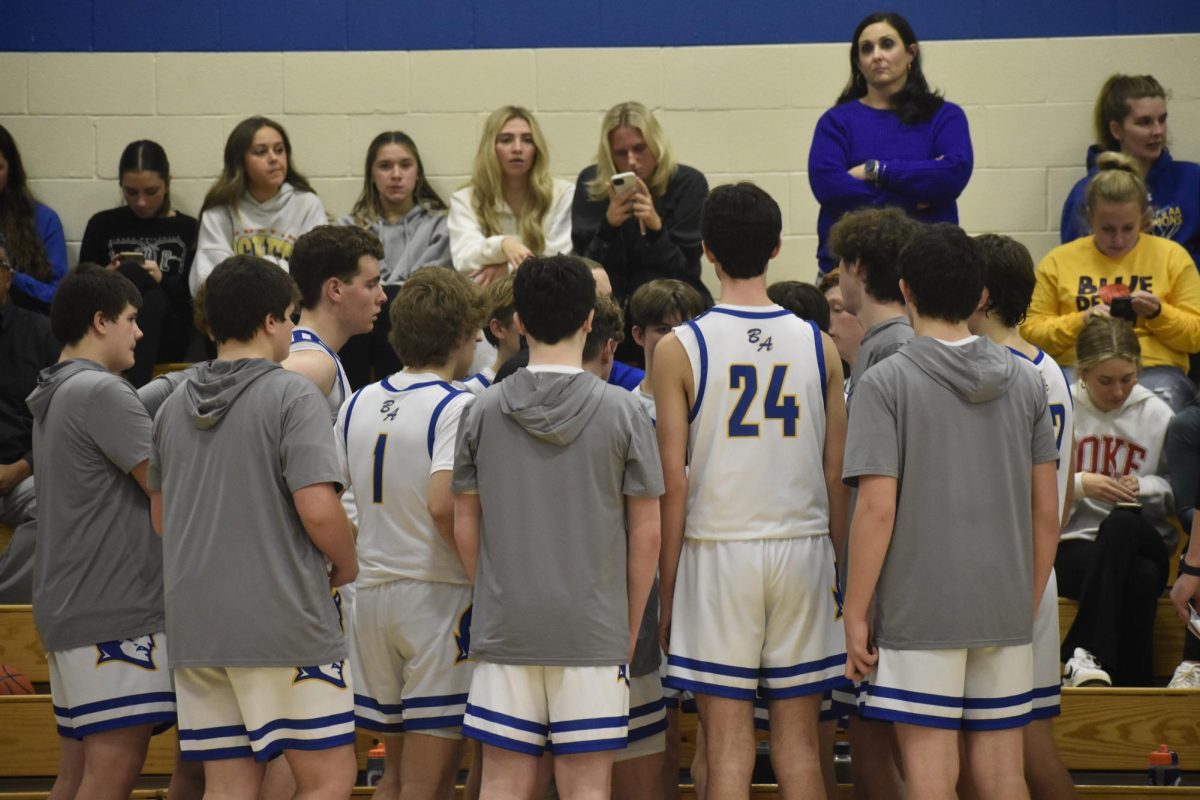Varsity boys basketball team in a huddle during a time out. 